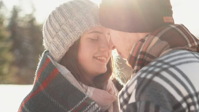 Young couple sharing moments of happiness hugging and exchanging tender touches in snowy clearing close-up portrait Winter romance in lovers of a man and a woman
