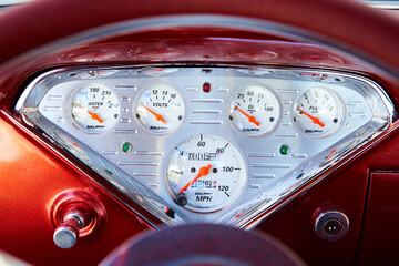 Control panel of a classic car from the 40's or 50's. Silver with red borders. Gas, speed, water.