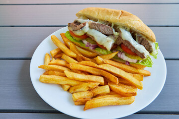 Beef and vegetable sandwich with french fries.