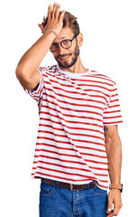 Fototapeta premium Handsome blond man with beard wearing casual clothes and glasses surprised with hand on head for mistake, remember error. forgot, bad memory concept.