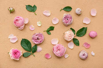 Fototapeta na wymiar Beautiful pink roses with leaves and petals on beige background