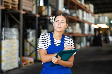 Young woman warehouse worker in uniform check documents in warehouse