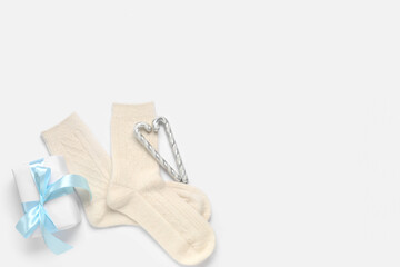Knitted socks with Christmas gift box and candy canes on white background