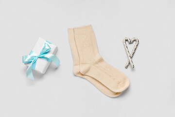 Knitted socks with Christmas gift box and candy canes on white background