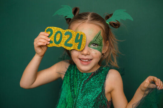 A girl dressed as a dragon with a painted face closes her eye with the number 2024. The symbol of the new year according to the Chinese calendar
