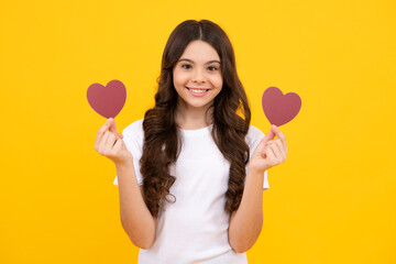 Cheerful lovely romantic teen girl hold red heart symbol of love for valentines day isolated on yellow background.
