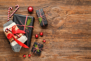 Knitted socks with Christmas decorations and gift boxes on wooden background