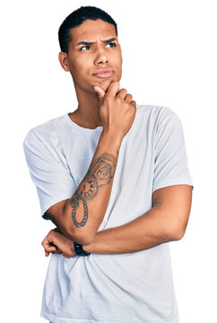 Young hispanic man wearing casual white t shirt thinking worried about a question, concerned and nervous with hand on chin