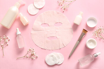 Obraz na płótnie Canvas Facial sheet mask with different cosmetic products and gypsophila flowers on pink background