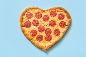 Tasty heart shaped pizza on blue background