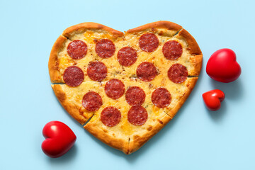 Tasty heart shaped pizza and beautiful decorations on blue background