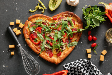 Tasty heart shaped pizza with ingredients on black background
