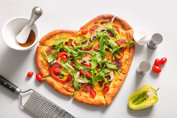 Tasty heart shaped pizza and ingredients on white background