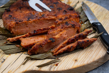 Vegan steak roasted in air fryer. Made of wheat gluten and tofu- seitan. Sliced, on wooden board, on banana leaf.