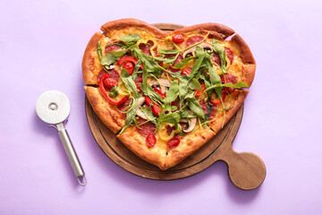 Wooden board with tasty heart shaped pizza and cutter on lilac background