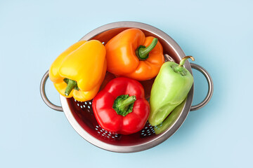 Colander with fresh bell peppers on blue background - obrazy, fototapety, plakaty