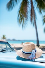 Fototapeta na wymiar Woman's straw hat on a hood of the blue car in Cuba