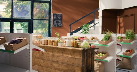 Fototapeta premium Chemicals free grains and vegetables in eco friendly zero waste supermarket. Organic farming produce and homemade sauces stored in reusable jars, empty store with sustainable lifestyle concept.