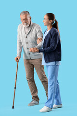 Senior man with walking stick and nurse on blue background