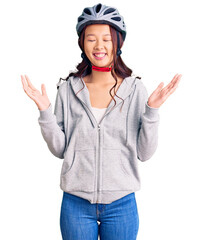 Young beautiful chinese girl wearing bike helmet celebrating mad and crazy for success with arms...