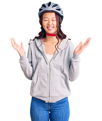 Young beautiful chinese girl wearing bike helmet celebrating mad and crazy for success with arms raised and closed eyes screaming excited. winner concept