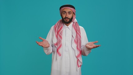 Islamic adult acting unsure and clueless in studio, showcasing i dont know sign and being confused...