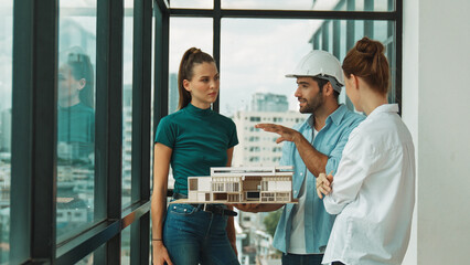 Skilled engineer holds house model and explain about house construction to skilled manager. Group of interior designer inspect architectural model. Working together, Civil engineering. Tracery - obrazy, fototapety, plakaty