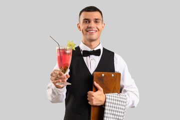 Young male bartender with glass of cocktail on white background