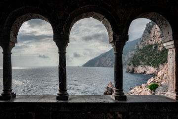 Arched stone window or opening in a stone wall overlooking scenic landscape of ligurian sea and...
