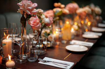 Beautiful table setting for wedding or another catered event dinner. Blurry candles with warm...