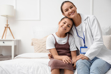 Sick little girl with doctor hugging in bedroom