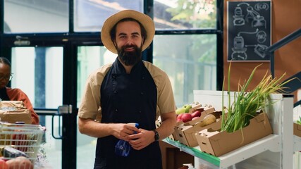 Small business owner in zero waste store arranging organic products on shelves, preparing local...