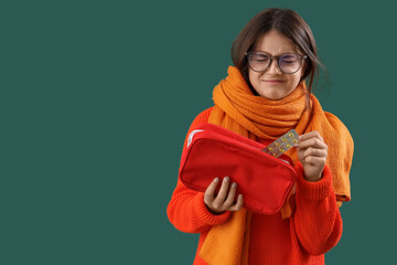 Obraz premium Sick little girl with first aid kit on green background