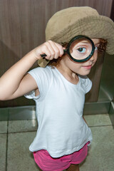 Girl with magnifying glass playing detective and investigating clues