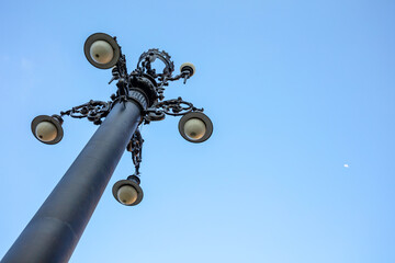 View from below of old public lighting pole with blue sky, historic center of São Paulo