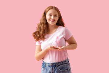 Young redhead woman with pink ribbon on color background. Breast cancer awareness concept