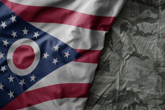 waving flag of ohio state on the old khaki texture background. military concept.