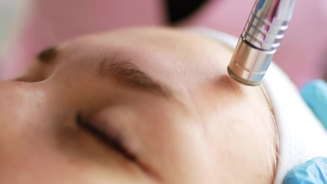 Beautician cosmetologist makes a procedure Microdermabrasion peeling of the face skin. Hardware cosmetology in clinic salon for client. Diamond face clean.	