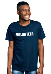 Young african american man wearing volunteer t shirt winking looking at the camera with sexy expression, cheerful and happy face.