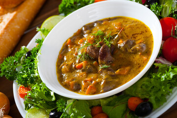 Delicious goulash of chicken hearts served on platter with fresh vegetables..