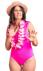 Young beautiful brunette woman wearing swimwear and hawaiian lei disgusted expression, displeased...