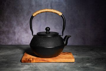 Traditional Asian cast iron kettle on a gray table.