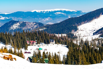 Aerial view ski slope,spruce pine trees,village rural house,hotels covered in snow in winter forest...