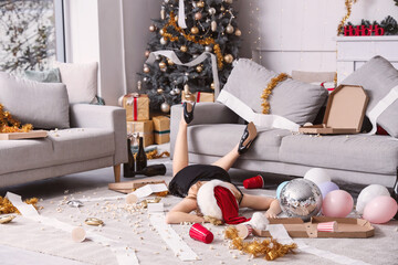 Drunk young woman lying on floor in messy living room after New Year party