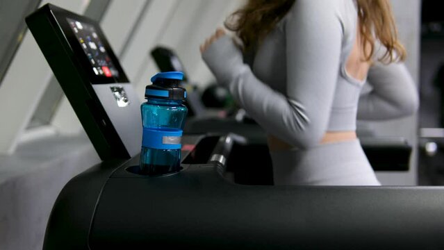 Portrait of sports woman with water. beautiful strong muscular woman drinking water in gym. young woman in grey sportswear with bottle of water. Fit thin gimnast sitting on stairs. High quality