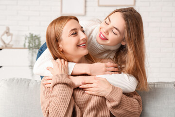 Beautiful young woman hugging her mother at home. International Hug Day
