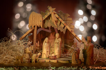 Hand carved wooden nativity set backlit by Christmas lights