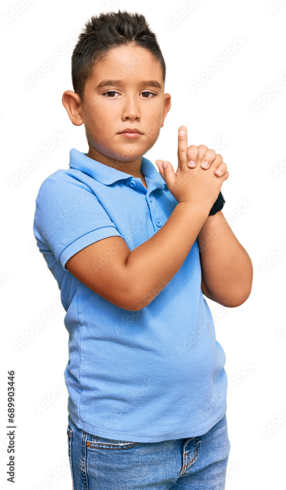 Wall mural Little boy hispanic kid wearing casual clothes holding symbolic gun with hand gesture, playing killing shooting weapons, angry face