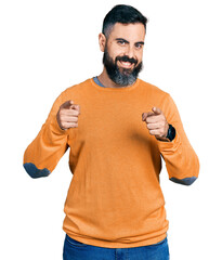 Hispanic man with beard wearing casual winter sweater pointing fingers to camera with happy and funny face. good energy and vibes.