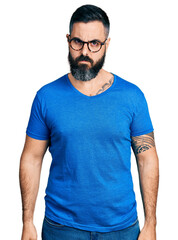 Hispanic man with beard wearing casual t shirt and glasses skeptic and nervous, frowning upset because of problem. negative person.